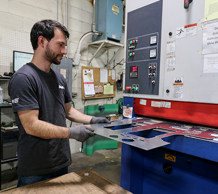 Employee placing metal into deburring machine