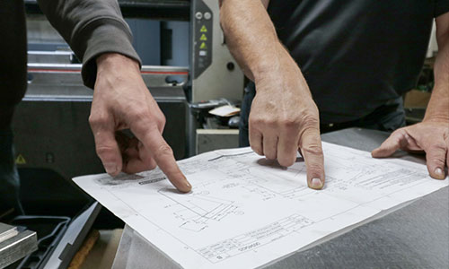 Employees pointing out measurement on a blueprint