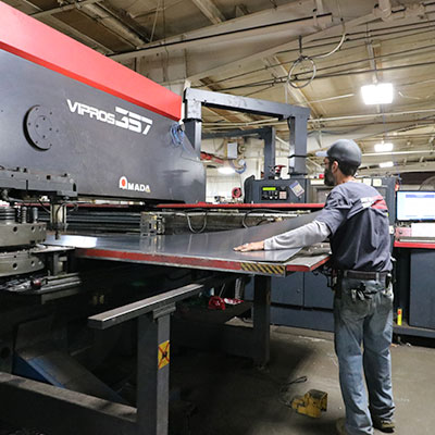Employee placing sheet metal into machine